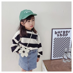 Detail of beaded flower mini bag styled with a striped sweatshirt and green cap