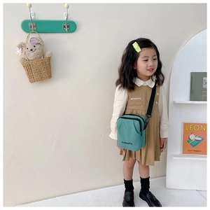 Close-up of children's teal canvas crossbody bag with adjustable strap and logo detail
