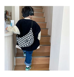 Detail view of checkerboard crossbody bag with adjustable strap and fashion patch on back