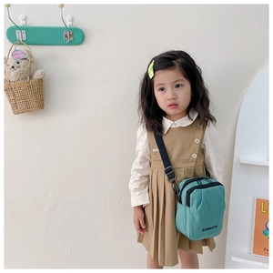 Detail of teal canvas kids crossbody bag with adjustable strap and KuHaoPai logo on front