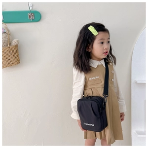 Detail view of child wearing black canvas crossbody bag with adjustable strap and metal zipper