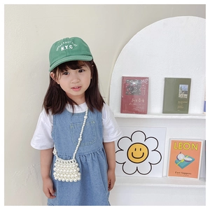 Close-up of a child wearing a handmade white pearl beaded crossbody bag with floral detail
