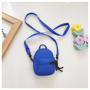 Flat lay of mini blue canvas crossbody bag for kids with adjustable strap on white surface