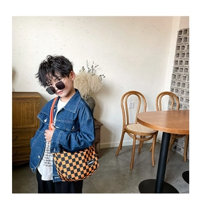 Detail view of stylish orange checkerboard crossbody bag for kids with fashion logo