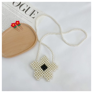 Macro detail of handmade pearl beaded flower bag for girls with black center accent