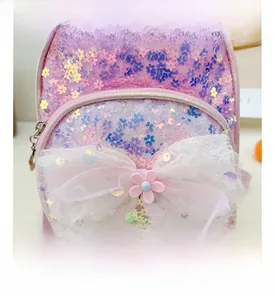 Détail du sac à dos à paillettes roses avec un nœud en dentelle blanche et fleur rose