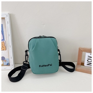 Detail of mint green nylon crossbody bag with black zipper and adjustable strap