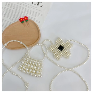 Macro detail of handmade beaded pearl mini bag with flower charm and metal hair clips