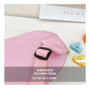Detail of adjustable pink canvas shoulder strap with black buckle and fabric texture