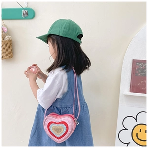 Close-up of pink heart-shaped kids crossbody bag with shiny red and blue sequins