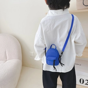 Mini blue canvas crossbody bag for kids with adjustable strap shown on a small child