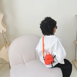 Minimalist orange nylon mini crossbody bag for kids shown on a child model back view