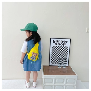Detail view of a yellow canvas crossbody bag with a cute cartoon bear print for kids