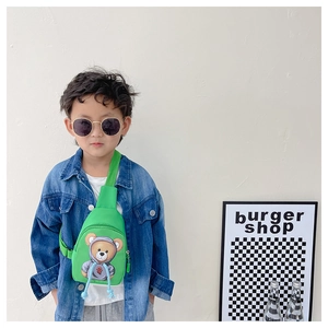 Toddler model wearing a green canvas crossbody bag with a cute teddy bear print