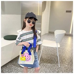 Kids carrying a cream canvas tote bag with a pink smiley face and bright blue strap