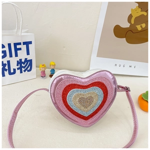 Detail of pink heart-shaped crossbody bag with multi-color glitter layers and slim strap