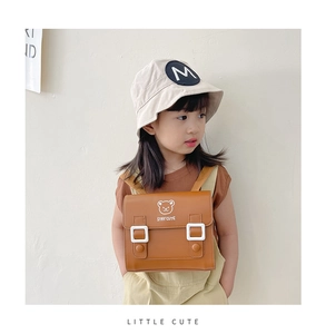 Detail of child wearing a brown PU leather backpack with a white bear and Stay Cute logo