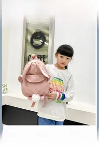 Pink cartoon rabbit backpack for kids with long ears and pom-pom detail on a child model