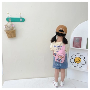 Pink canvas kids chest bag with cartoon bear print shown on a model in a cozy room