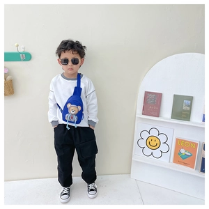 Blue kids crossbody chest bag with cute cartoon bear pattern worn by a young boy