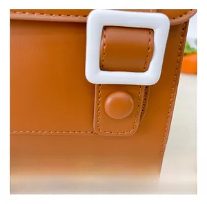 Detail of premium brown faux leather stitching and white decorative square buckle on bag