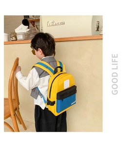 Sac à dos pour enfant avec design color-block jaune et bleu dans un café cosy