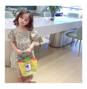 Détail d'un sac à main en maille jaune pour fille avec patchs fleuris et robe d'été