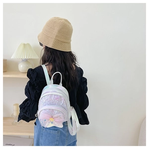 Détail d'un mini sac à dos pailleté en cuir laser avec un nœud en tulle rose au dos