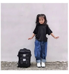 Detail view of black nylon kids backpack featuring white NY embroidery and buckle pockets