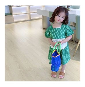 Détail d'un sac à main en maille bleue assorti à une robe verte à pois pour fille