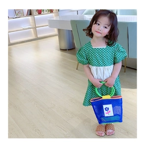 Détail de la robe verte à pois pour fille avec son sac à main assorti en maille bleue