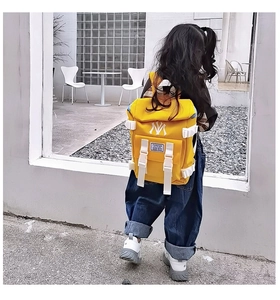 Detail showing the white NY logo and FASHION label on the yellow nylon kids backpack