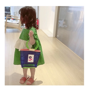 Détail d'un petit sac à main tissé bleu pour fille avec fleur mauve et anses vertes