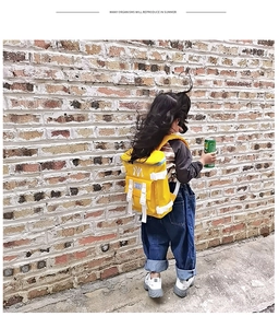 Detail of a lightweight yellow nylon kids backpack featuring white NY embroidery and buckles