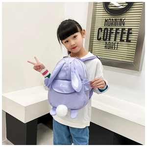 Detail view of a cute purple rabbit backpack with long ears on a child model outdoors