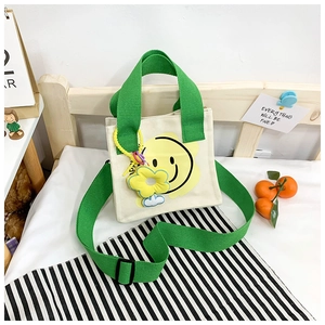 Detail of kids canvas tote bag with yellow smiley face print and green handles