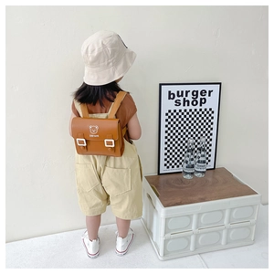 Toddler wearing brown PU leather backpack with Stay Cute print in a minimalist studio