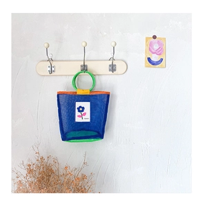 Détail du sac de plage en filet bleu pour enfants avec poignée ronde verte sur crochet