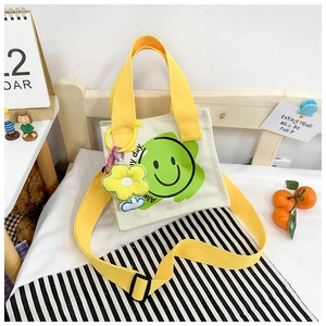 Detail of cream canvas bag featuring a green smiley flower and yellow strap