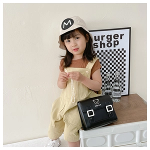 Detail of a black leather kids crossbody bag featuring a cute bear and text slogan