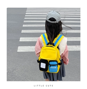 Rear view of a child wearing the yellow canvas backpack with blue straps on a crosswalk