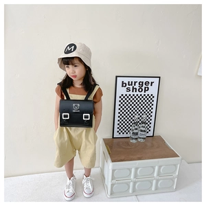 Detail of child wearing a black PU messenger bag with bear print and Stay Cute text