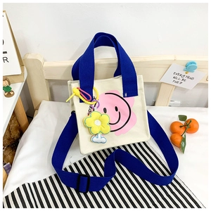 Detailed view of smiley face canvas tote with blue handles and sunflower charm
