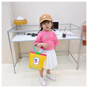 Detail of yellow mesh tote bag for children with blue flower motifs and colorful handles