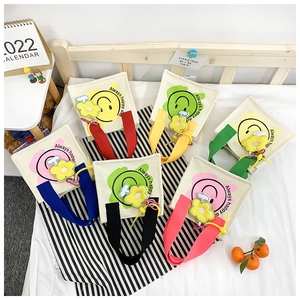 Flat lay of colorful smiley canvas tote bags with flower pendants on striped background
