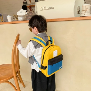 Sac à dos pour enfant aux couleurs contrastées jaune, bleu et noir dans un café