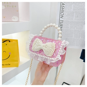 Detail of pink sequin girl's purse featuring large pearl bow and delicate lace trim