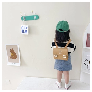 Detail of khaki PU leather kids backpack featuring bear logo and adjustable buckles