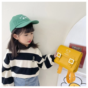 Close-up of bright yellow retro PU kids backpack with cute bear print and stay cute text
