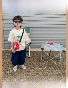 Détail d'un sac bandoulière rouge pour enfant en toile avec impression de lettres blanches